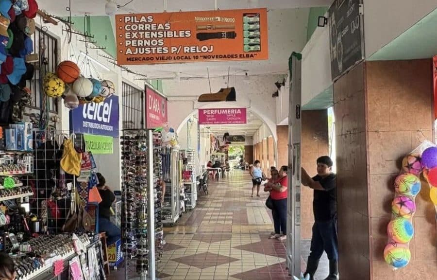 Interior de mercado local en Chetumal con varios locales comerciales, algunos con clientes y otros aparentemente vacíos.