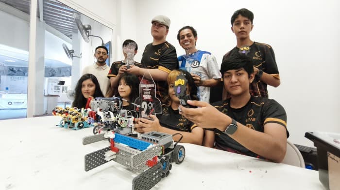 Estudiantes del club de robótica del Planetario Sayab muestran sus proyectos de robots y soluciones tecnológicas en una sala de trabajo.