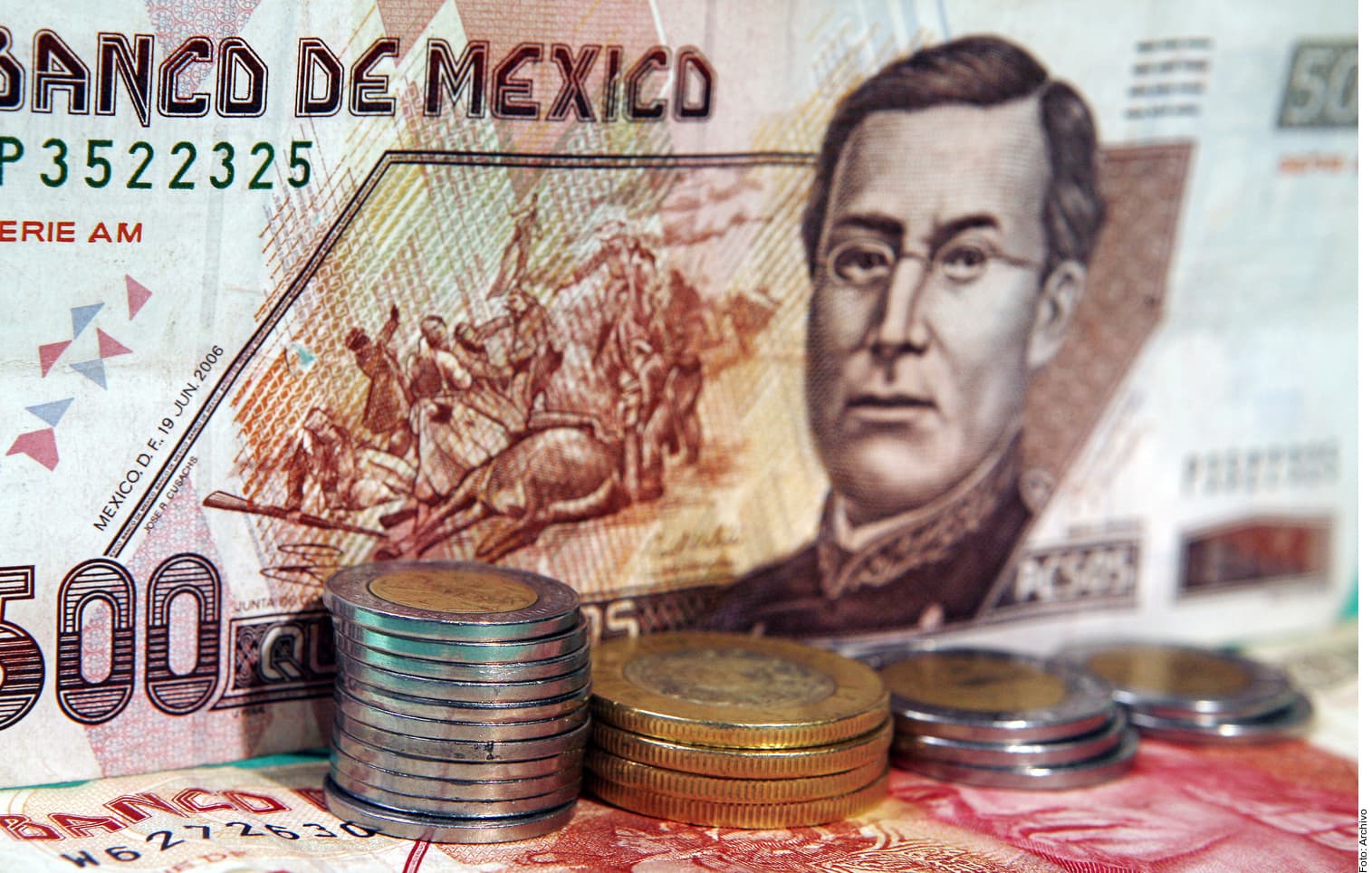 Billetes y monedas de pesos mexicanos sobre fondo con el Banco de México.