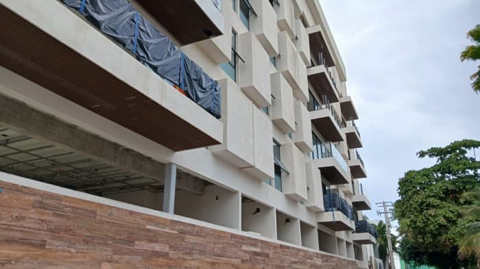 Edificio de apartamentos en construcción o remodelación con múltiples pisos y balcones visibles.