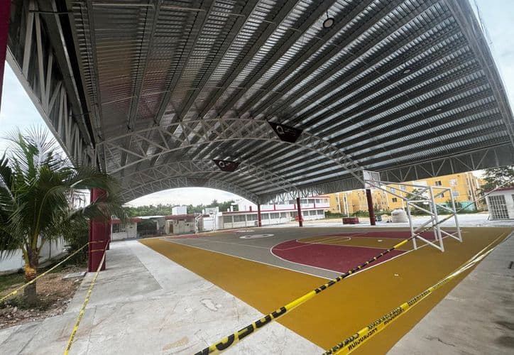 Domo deportivo en construcción con estructura metálica de acero y cancha de color amarillo y rojo visible bajo la cobertura.