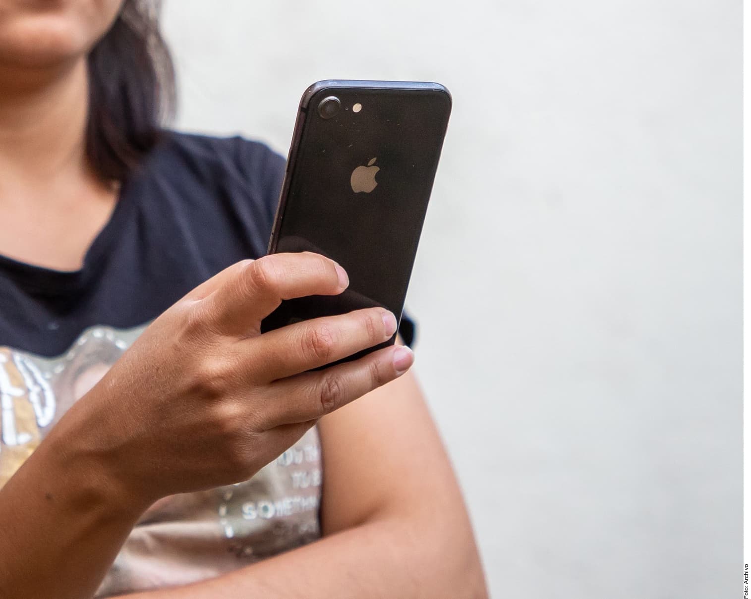Persona sostiene un iPhone negro mostrando el logo de Apple en la parte trasera.