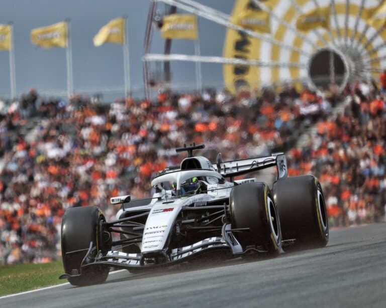 Monoplaza de Fórmula 1 de color blanco durante una carrera en circuito con público en las gradas de fondo.