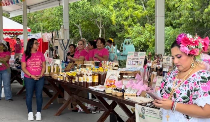 Vendedora de productos artesanales en un puesto de mercado al aire libre durante un evento comunitario en Playa del Carmen.