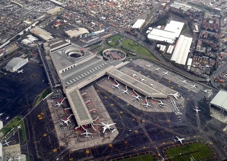 Vista aérea del Aeropuerto Internacional Benito Juárez de la Ciudad de México mostrando múltiples aviones estacionados en las pistas y plataformas.