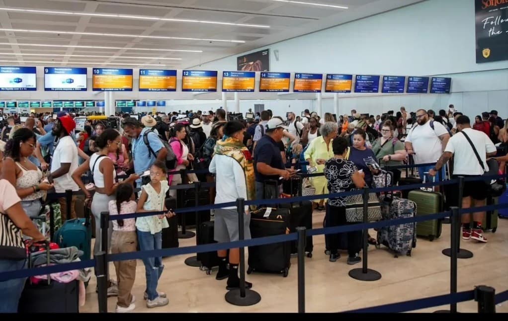 Pasajeros en fila en la zona de mostradores del aeropuerto de Cancún durante operación de check-in.