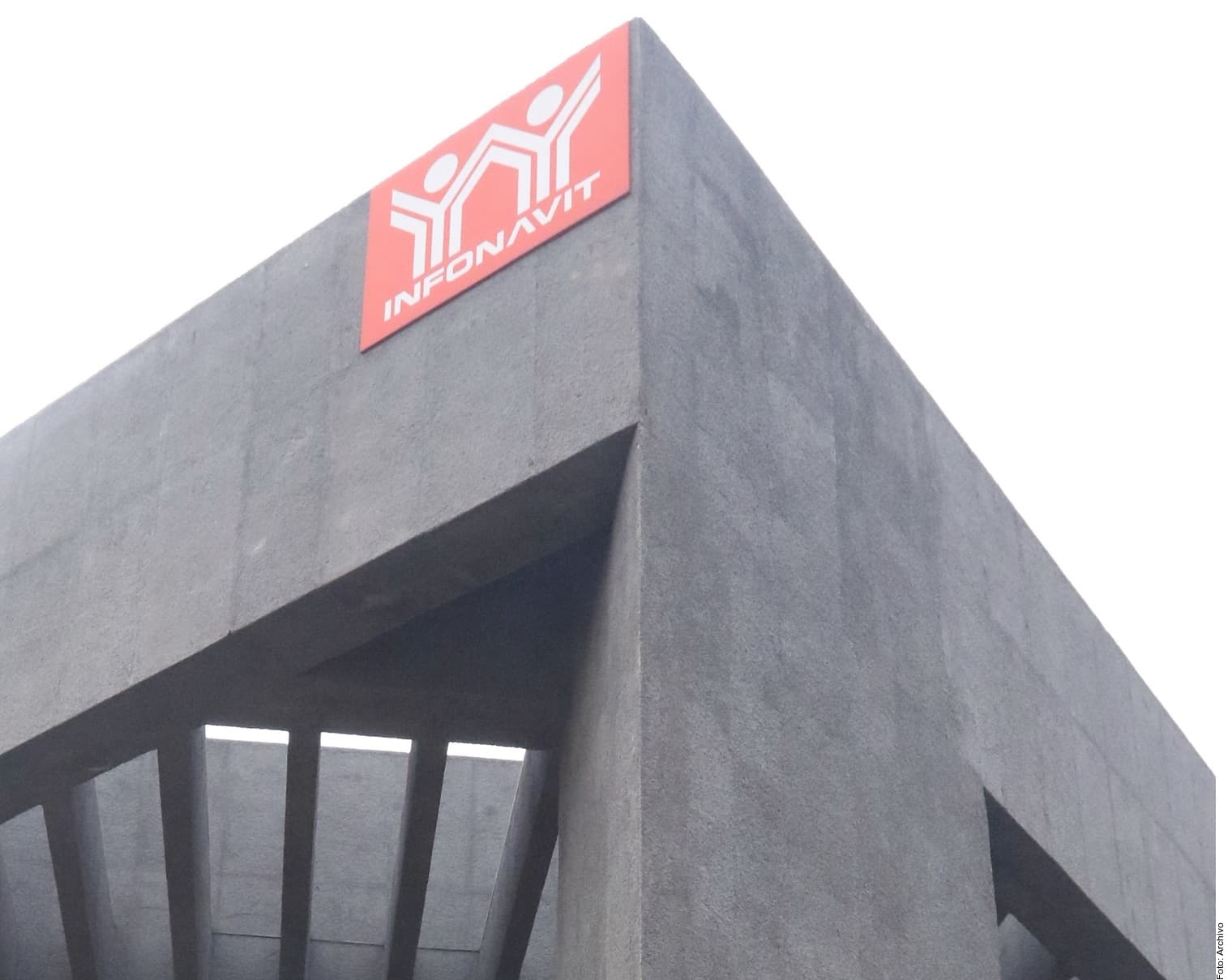 Edificio de concreto gris con letrero luminoso rojo de Infonavit en la fachada superior.