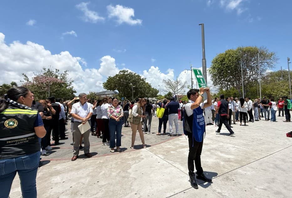 Cientos de personas participan en un simulacro de emergencia en una plaza pública bajo un cielo despejado.
