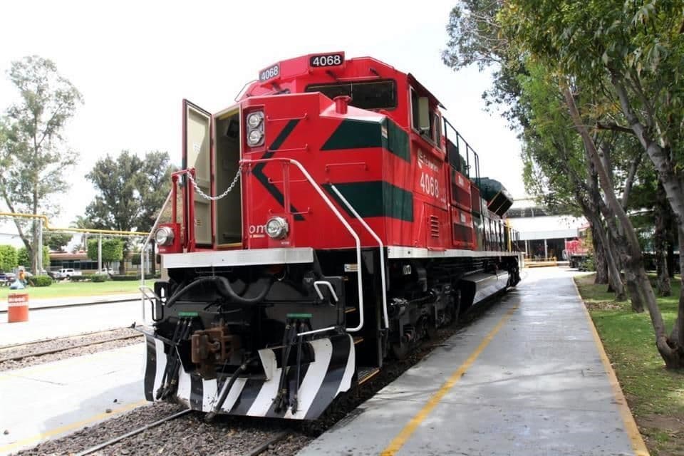 Locomotora roja número 4068 de tren de carga estacionada en una vía junto a una acera arbolada.