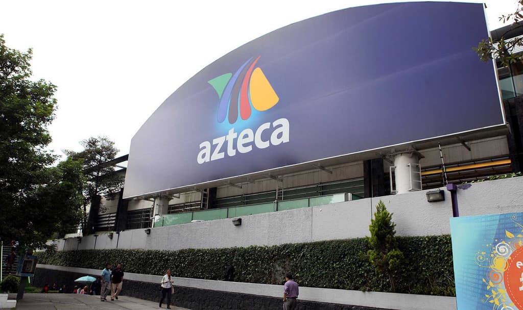 Fachada de las instalaciones de TV Azteca con su logo corporativo en una pantalla digital azul.