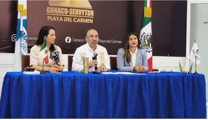 Tres personas en panel de discusión alrededor de mesa azul con bandera mexicana y logo de Canaco-Servytur de fondo.