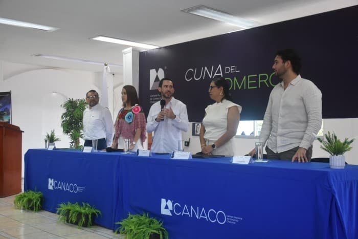 Panel de cinco personas en una mesa con mantel azul de CANACO durante un evento sobre turismo e inteligencia artificial en Quintana Roo.