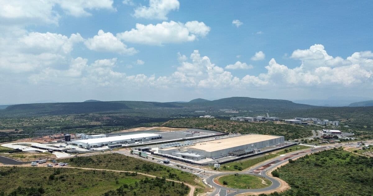 Complejos industriales modernos con naves de almacenamiento y oficinas rodeados de vegetación en región montañosa.