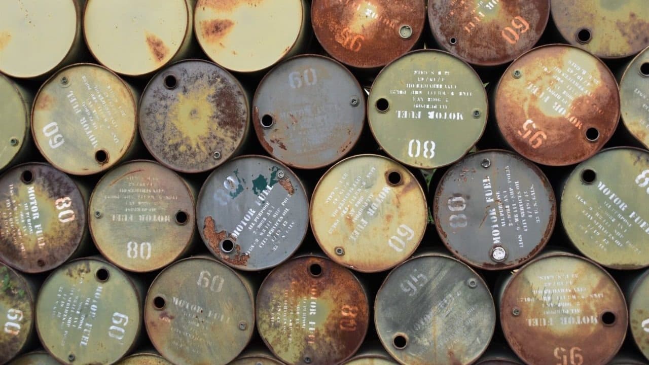 Barriles metálicos apilados con números de identificación y marcas de desgaste por oxidación.
