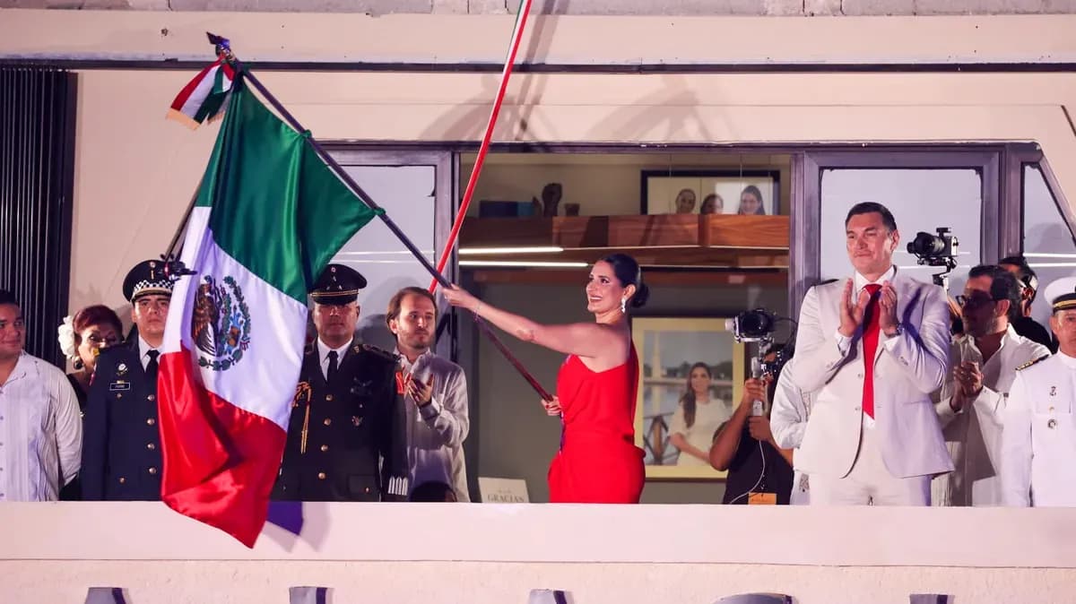 Estefanía Mercado ondea la bandera de México desde el balcón del antiguo Palacio Municipal durante el Grito de Independencia en Playa del Carmen
