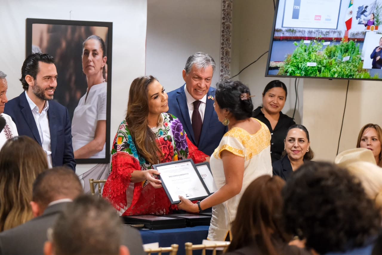 Mara Lezama entrega reconocimiento a una graduada del programa Mexicana Emprende 2026 durante ceremonia en Orlando, Florida, rodeada de autoridades y participantes.