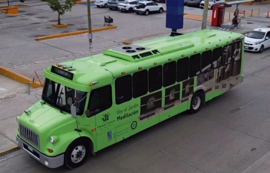 Autobús de transporte público de color verde brillante con publicidad del ChariBús estacionado en una plaza con vehículos de fondo.