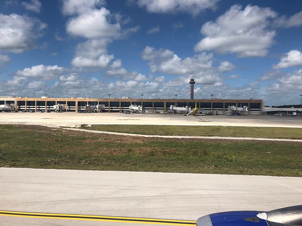 Terminal del Aeropuerto Internacional de Cancún con pistas de aterrizaje parcialmente vacías y equipos de servicio dispersos bajo cielo despejado.