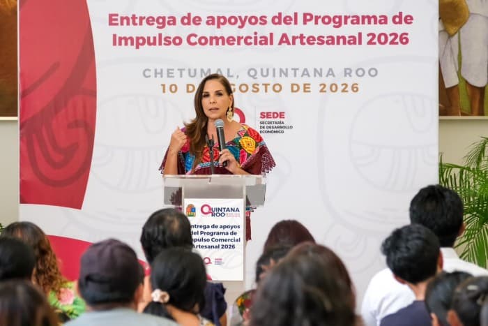 Mara Lezama, funcionaria, habla desde un podio durante la entrega de apoyos del Programa de Impulso Comercial Artesanal 2026 en Chetumal, Quintana Roo.