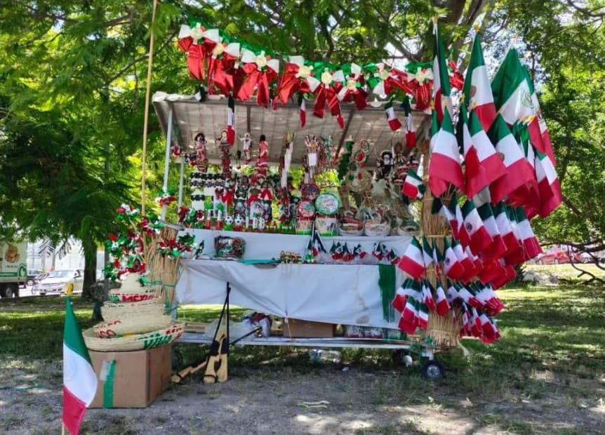 Puesto de venta decorado con banderas mexicanas y artículos patrióticos en rojo, blanco y verde.