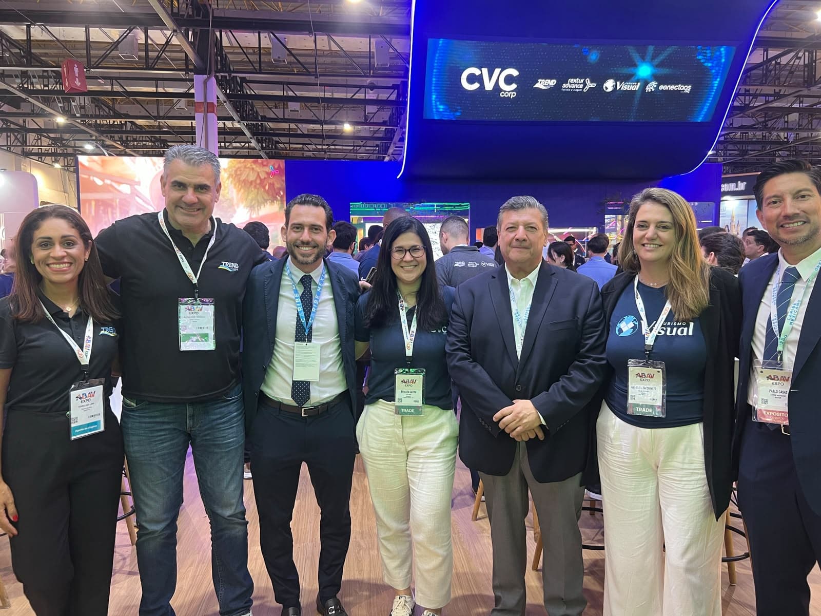 Grupo de profesionales del turismo y funcionarios posando juntos en la ABAV Expo con el stand de CVC Corp de fondo.